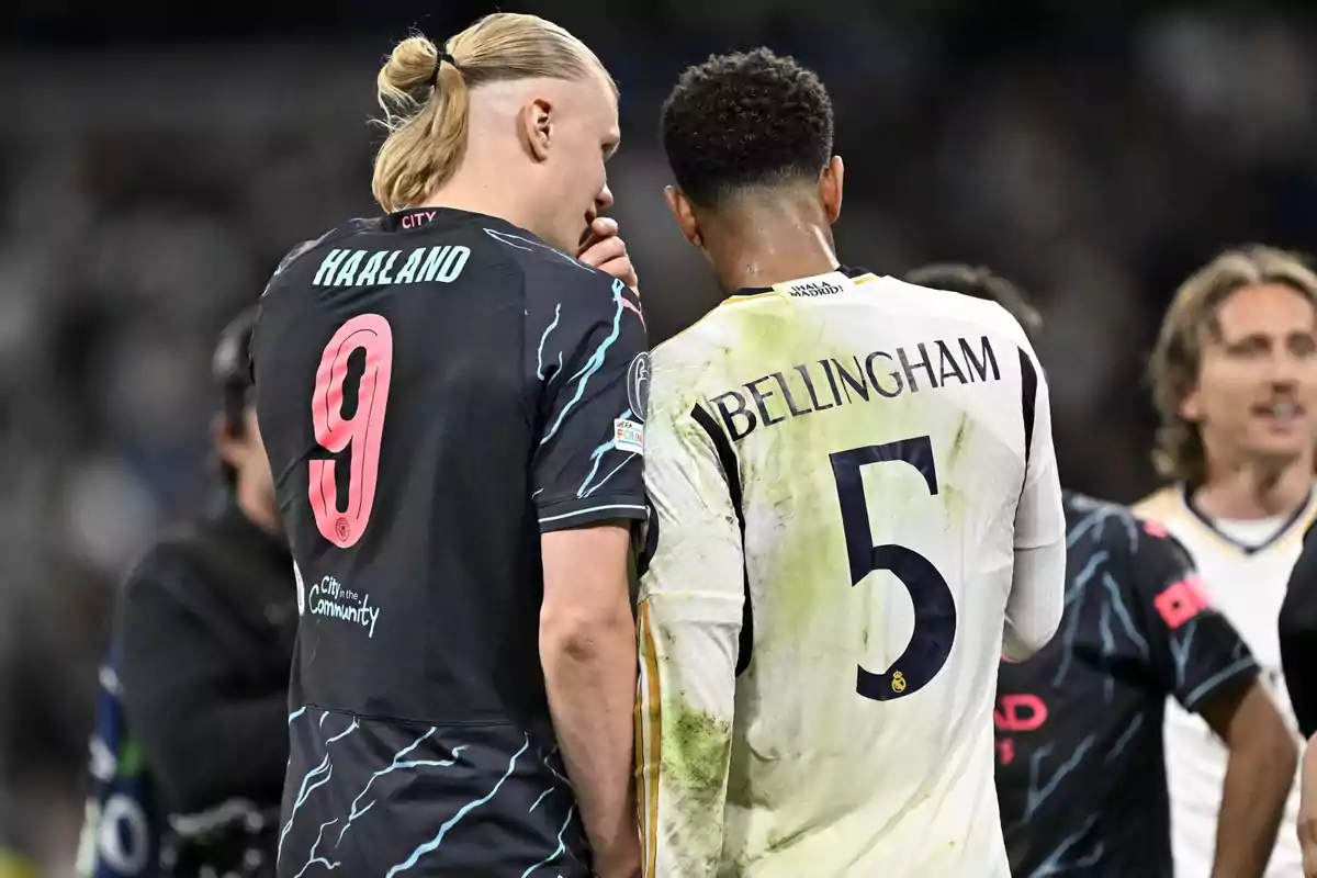 Dos futbolistas conversan en el campo al finalizar un partido, uno lleva la camiseta negra con el número 9 y el otro la camiseta blanca con el número 5 Dos futbolistas conversan en el campo al finalizar un partido, uno lleva la camiseta negra con el número 9 y el otro la camiseta blanca con el número 5