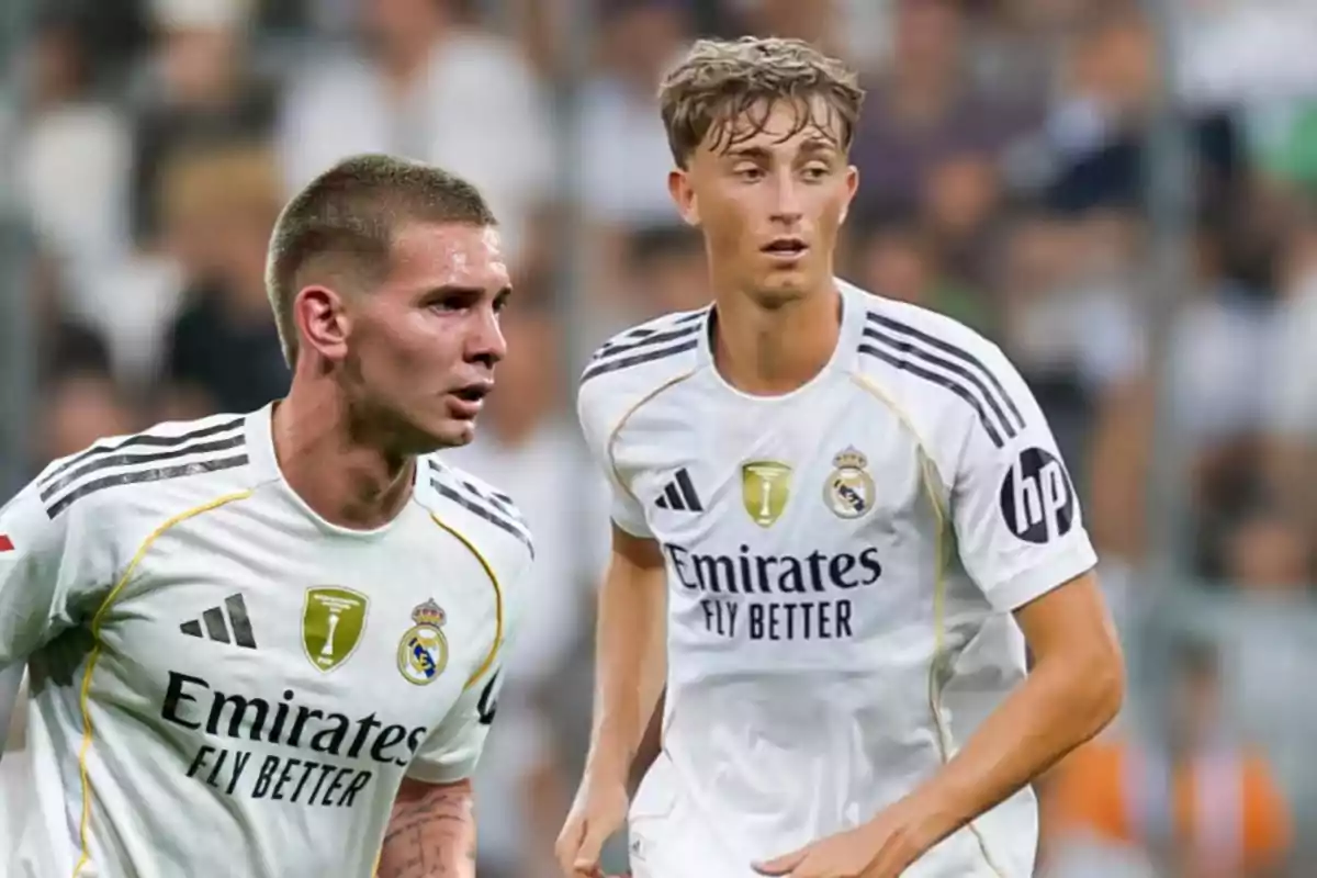 Two players in white Real Madrid uniforms during a match, one in the foreground and the other in the background, both with serious and focused expressions.