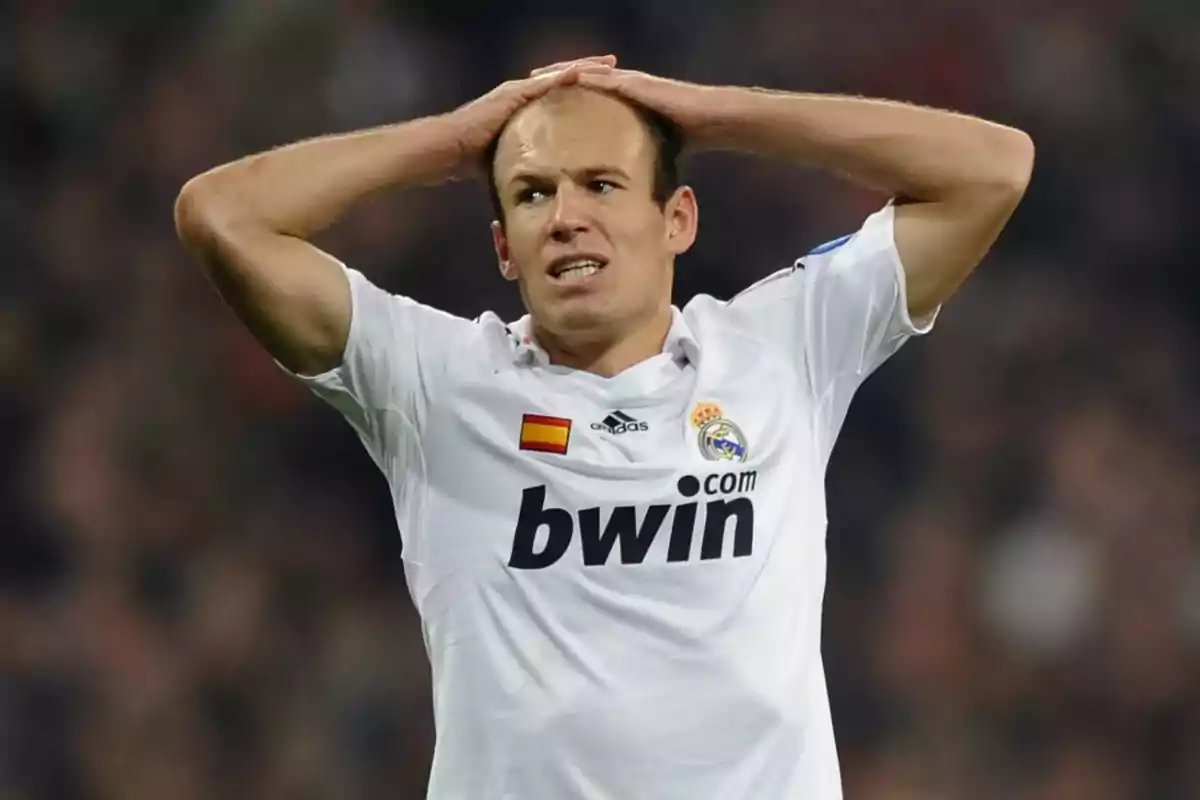 Soccer player in a white Real Madrid uniform puts his hands on his head and shows a frustrated expression on the field. Soccer player in a white Real Madrid uniform puts his hands on his head and shows a frustrated expression on the field.