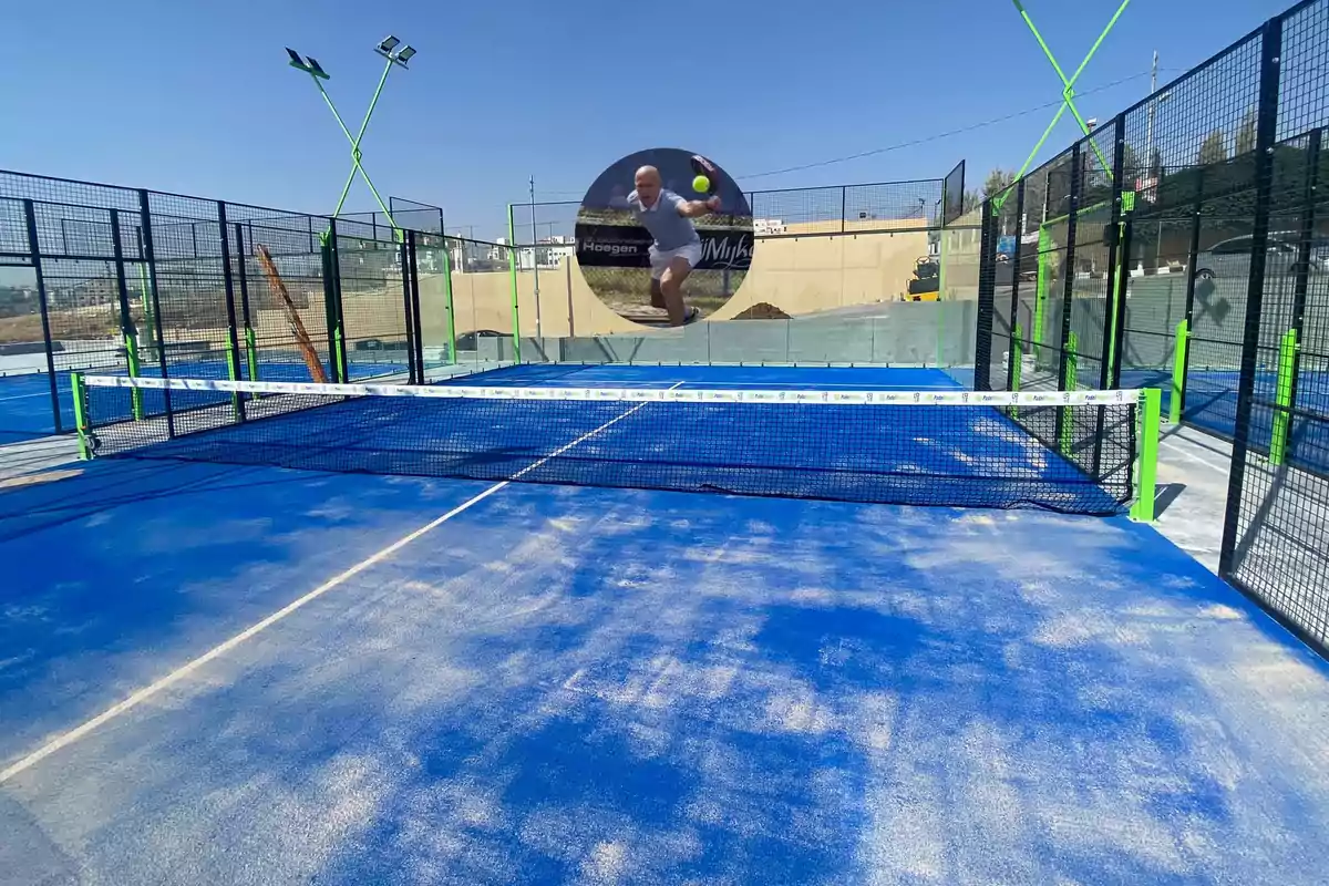 Padel court with a blue surface, net in the center, and an image of a player on the back exterior wall