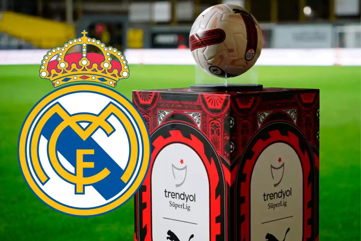 Logo del Real Madrid junto a un balón de fútbol de la Superliga turca sobre un pedestal en un estadio.