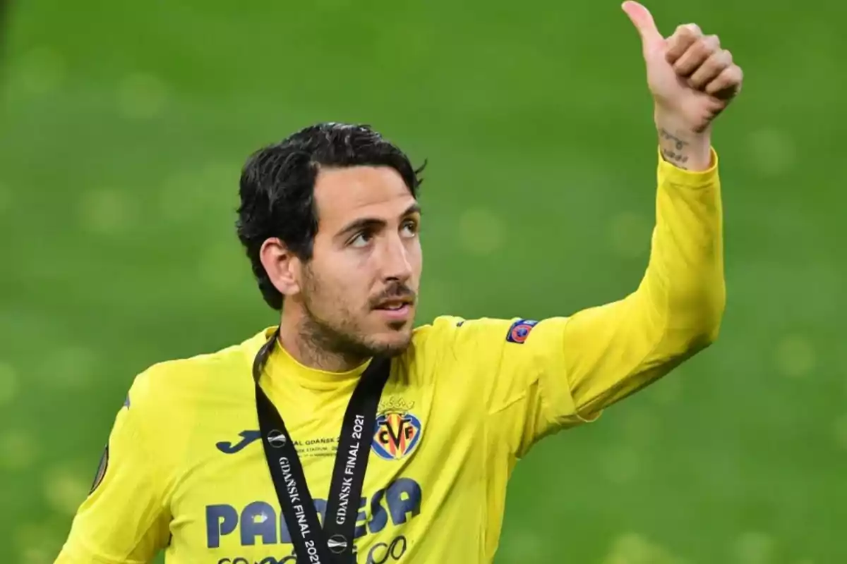 Football player in yellow uniform giving thumbs up and wearing a medal.