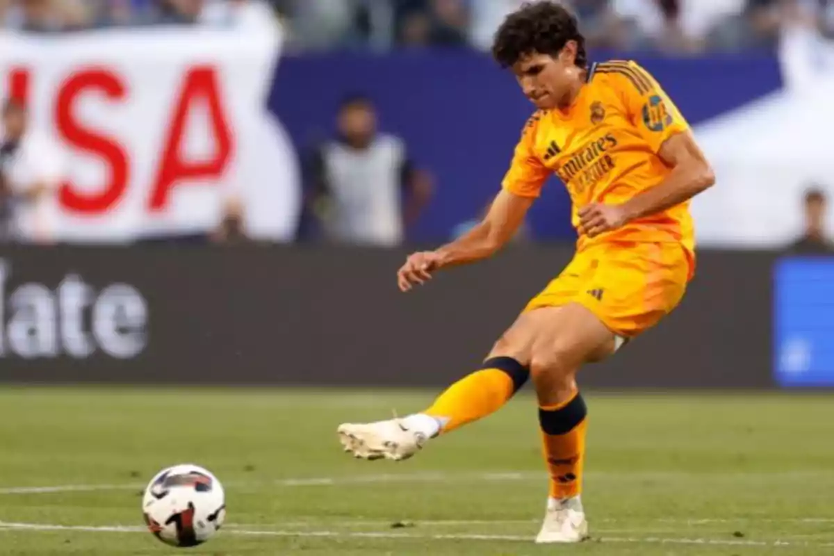 Jugador de fútbol con uniforme naranja pateando un balón en un campo de juego. Jugador de fútbol con uniforme naranja pateando un balón en un campo de juego.