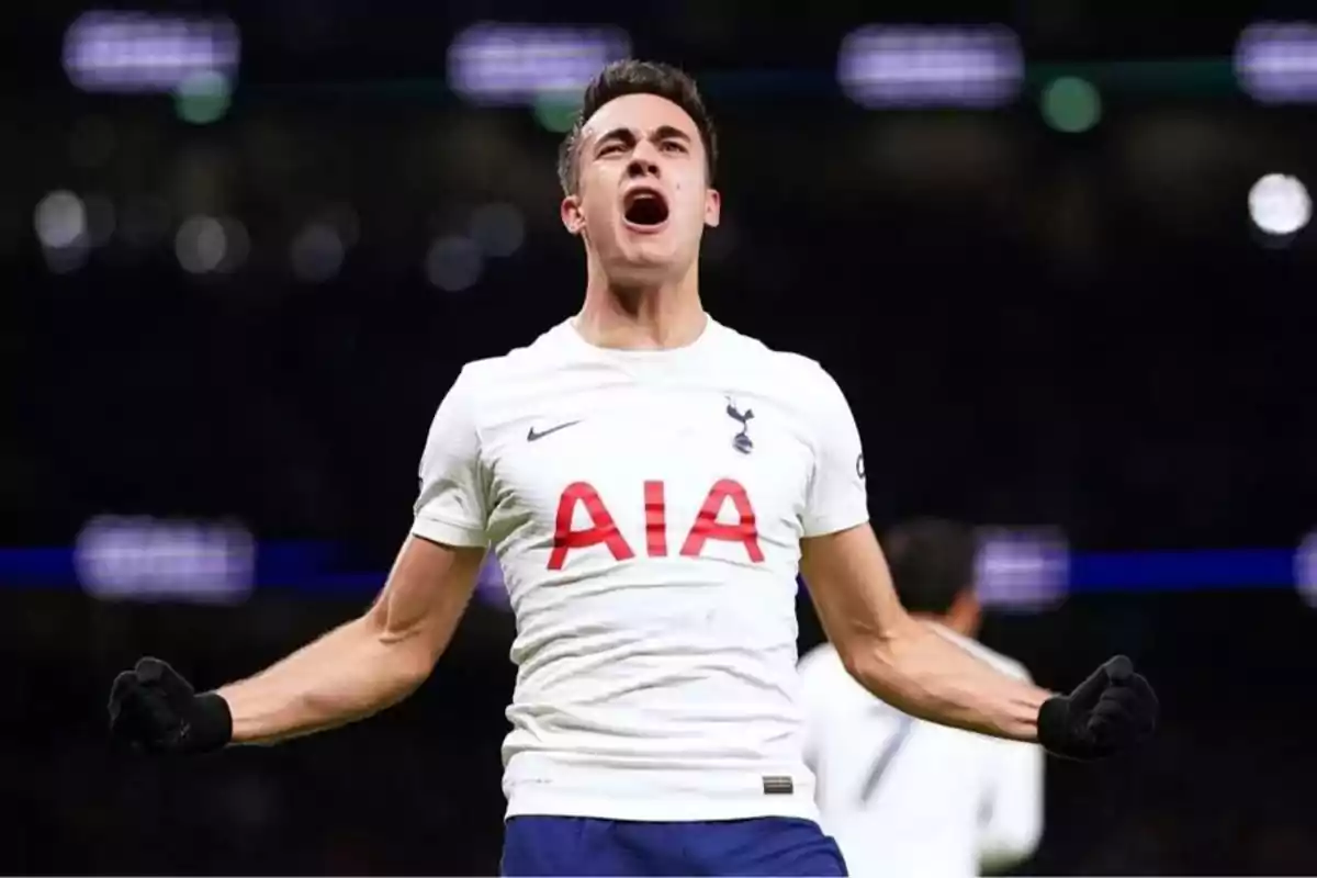 Jugador de fútbol celebrando con los brazos extendidos y vistiendo la camiseta del Tottenham Hotspur en un estadio iluminado. Jugador de fútbol celebrando con los brazos extendidos y vistiendo la camiseta del Tottenham Hotspur en un estadio iluminado.