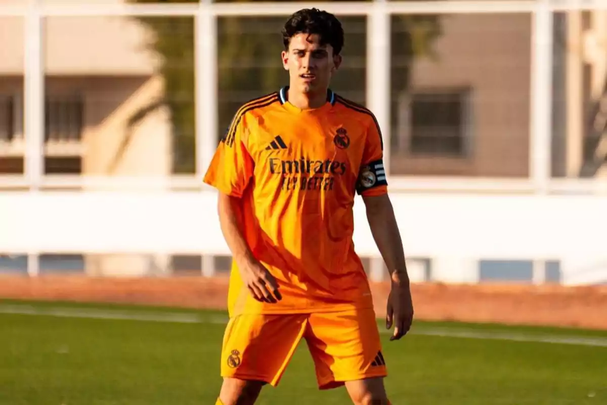 Un jugador de fútbol con uniforme naranja del Real Madrid en el campo.