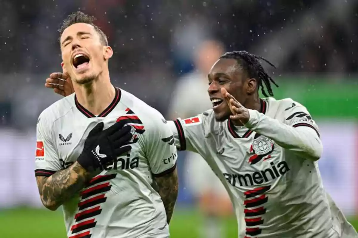 Dos futbolistas celebran un gol en el campo, uno con la mano en el pecho y el otro sonriendo y señalando. Dos futbolistas celebran un gol en el campo, uno con la mano en el pecho y el otro sonriendo y señalando.