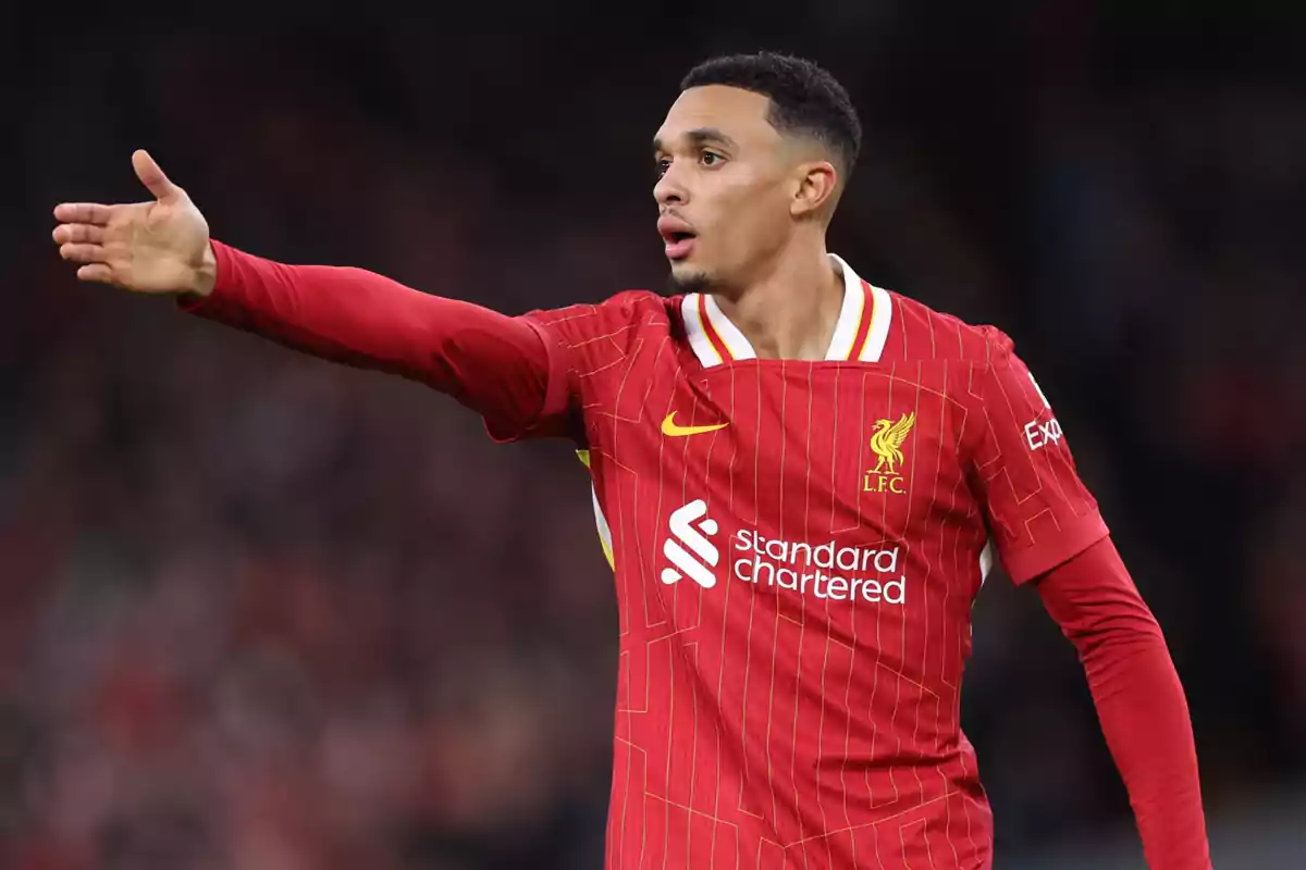 Football player in red Liverpool uniform gesturing on the field. Football player in red Liverpool uniform gesturing on the field.