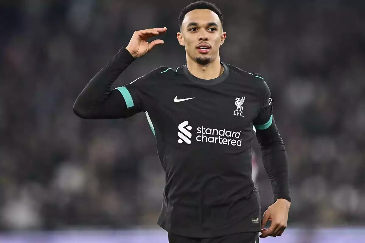 Football player in black Liverpool FC uniform on the playing field. Football player in black Liverpool FC uniform on the playing field.