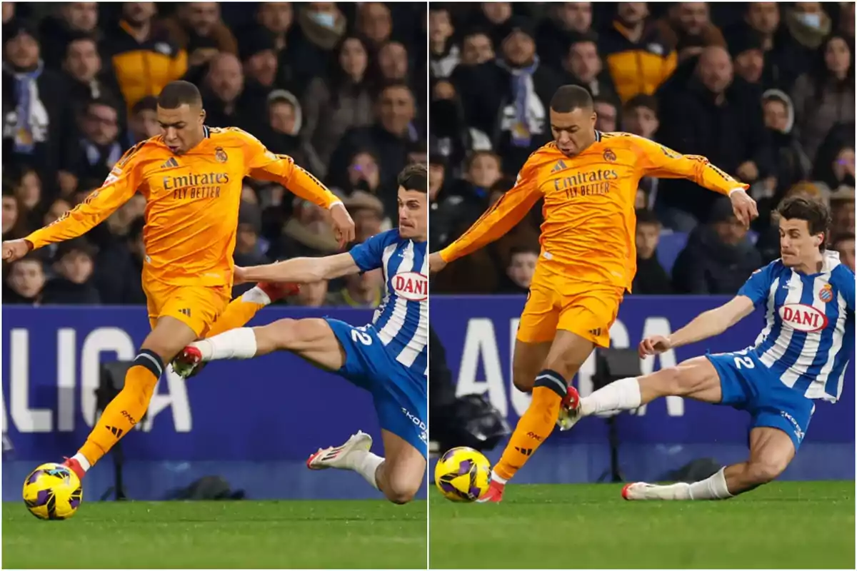 Dos jugadores de fútbol compiten por el balón en un partido, uno con uniforme naranja y el otro con uniforme azul y blanco, mientras el público observa desde las gradas.