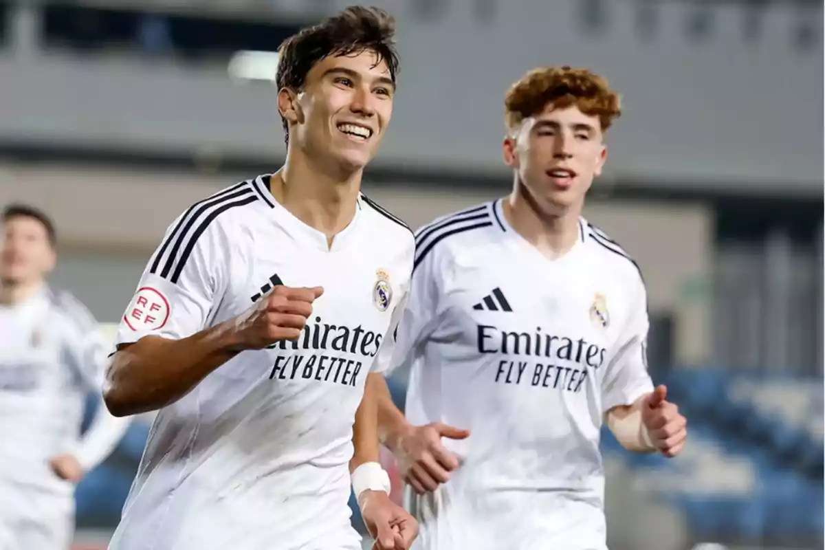 Two players in white Real Madrid uniforms run on the field smiling. Two players in white Real Madrid uniforms run on the field smiling.
