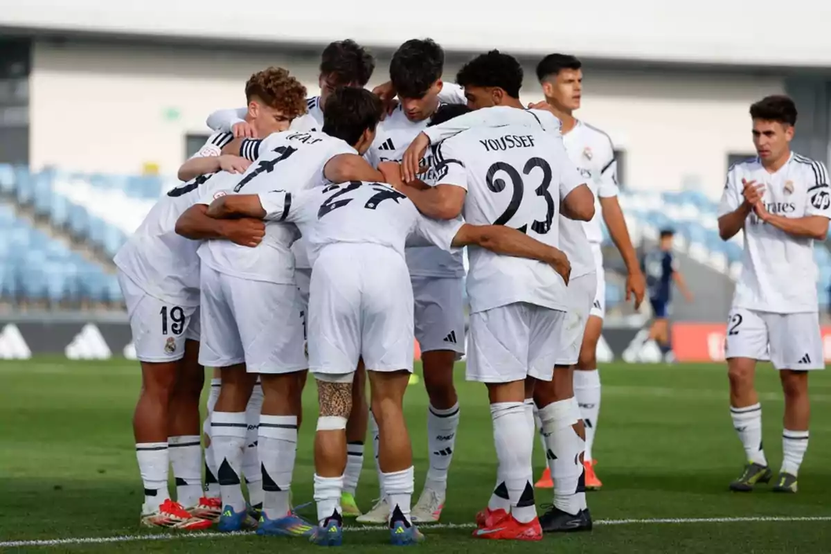 A group of players in white uniforms hug on the field while another player claps nearby. A group of players in white uniforms hug on the field while another player claps nearby.
