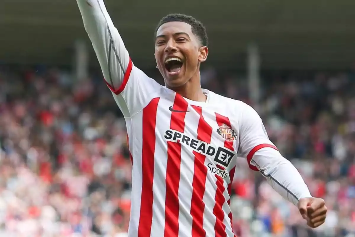 Soccer player celebrating a goal in a Sunderland uniform in a stadium full of fans Soccer player celebrating a goal in a Sunderland uniform in a stadium full of fans
