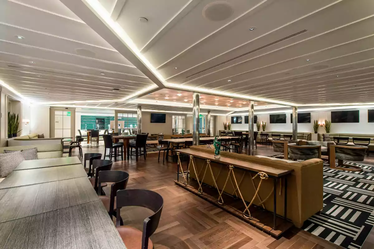 Modern and elegant interior space with tables, chairs, and sofas, warm lighting, and contemporary décor Modern and elegant interior space with tables, chairs, and sofas, warm lighting, and contemporary décor