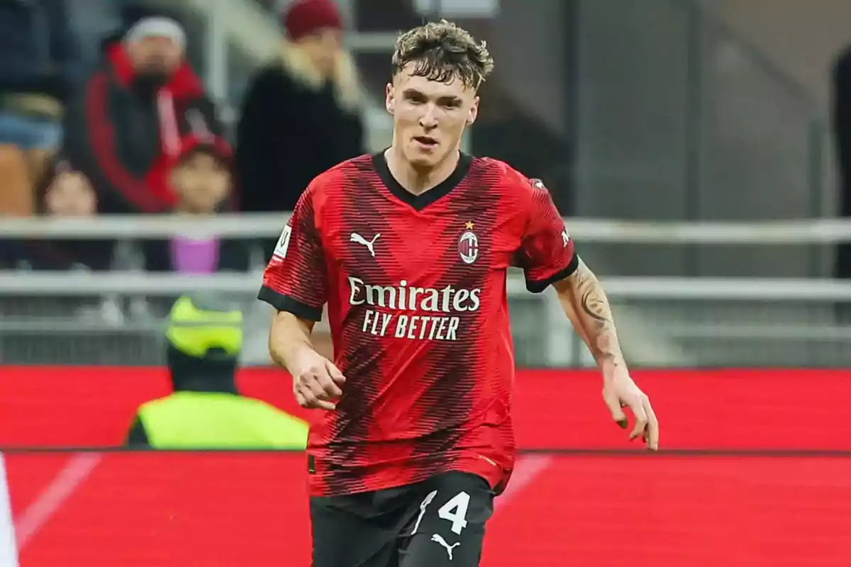 Jugador de fútbol con camiseta roja y negra del AC Milan en el campo de juego.