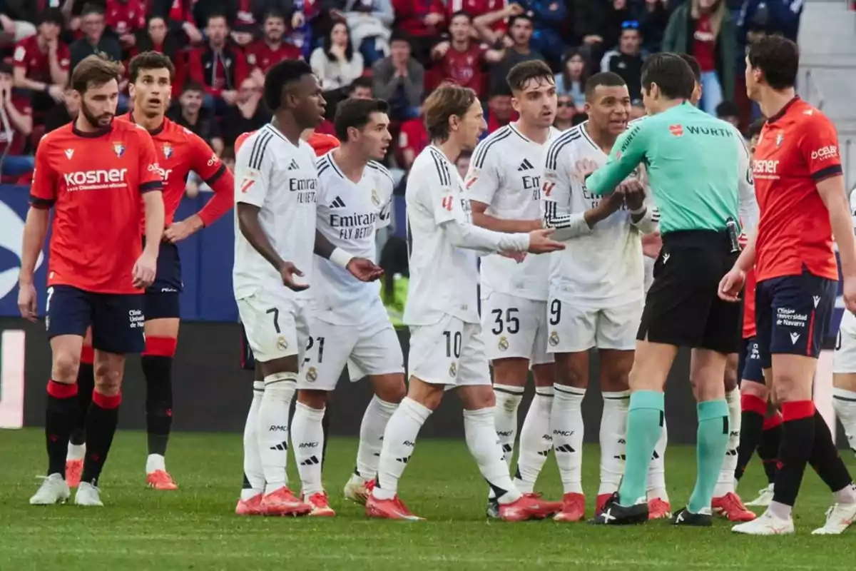 Soccer players from two teams argue with the referee on the field during a match.