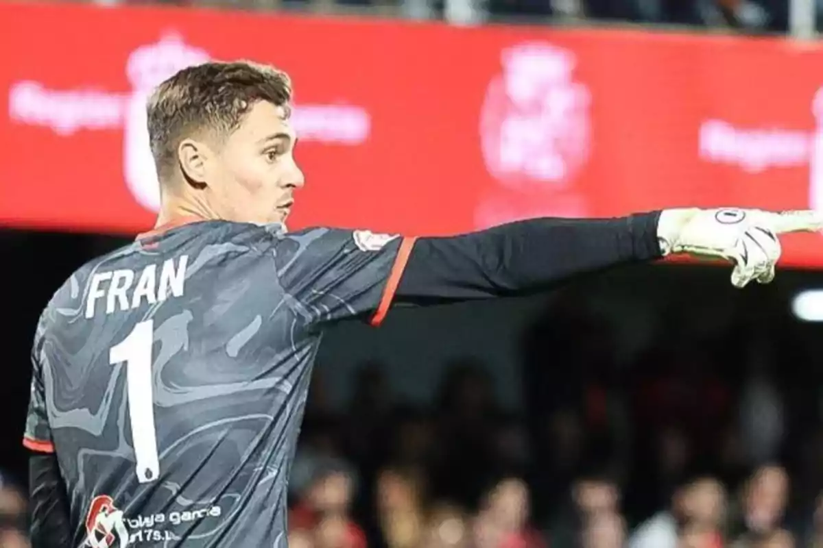 A soccer goalkeeper with gloves points to the side during a match. A soccer goalkeeper with gloves points to the side during a match.