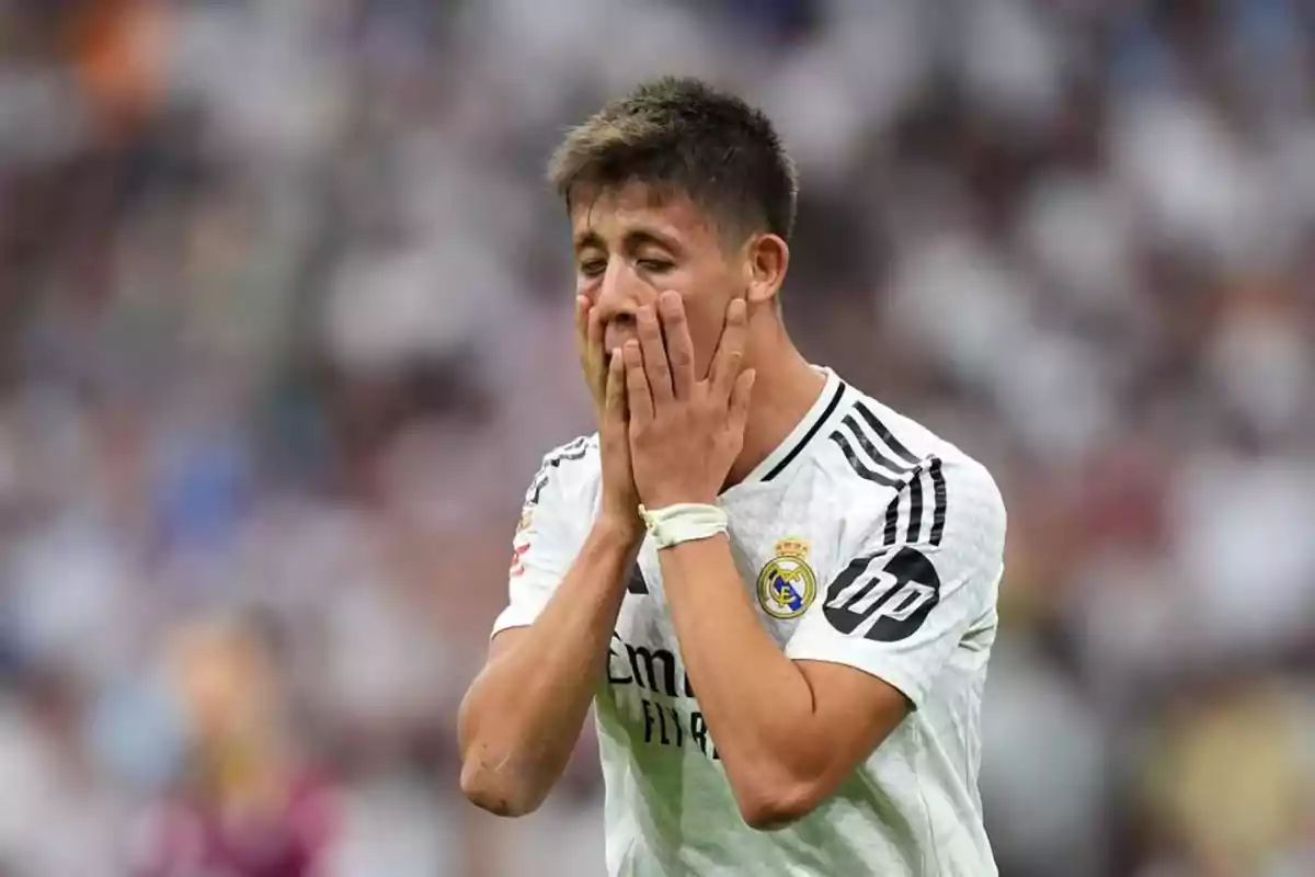 Un jugador de fútbol con el uniforme del Real Madrid se cubre el rostro con las manos en un campo de juego.