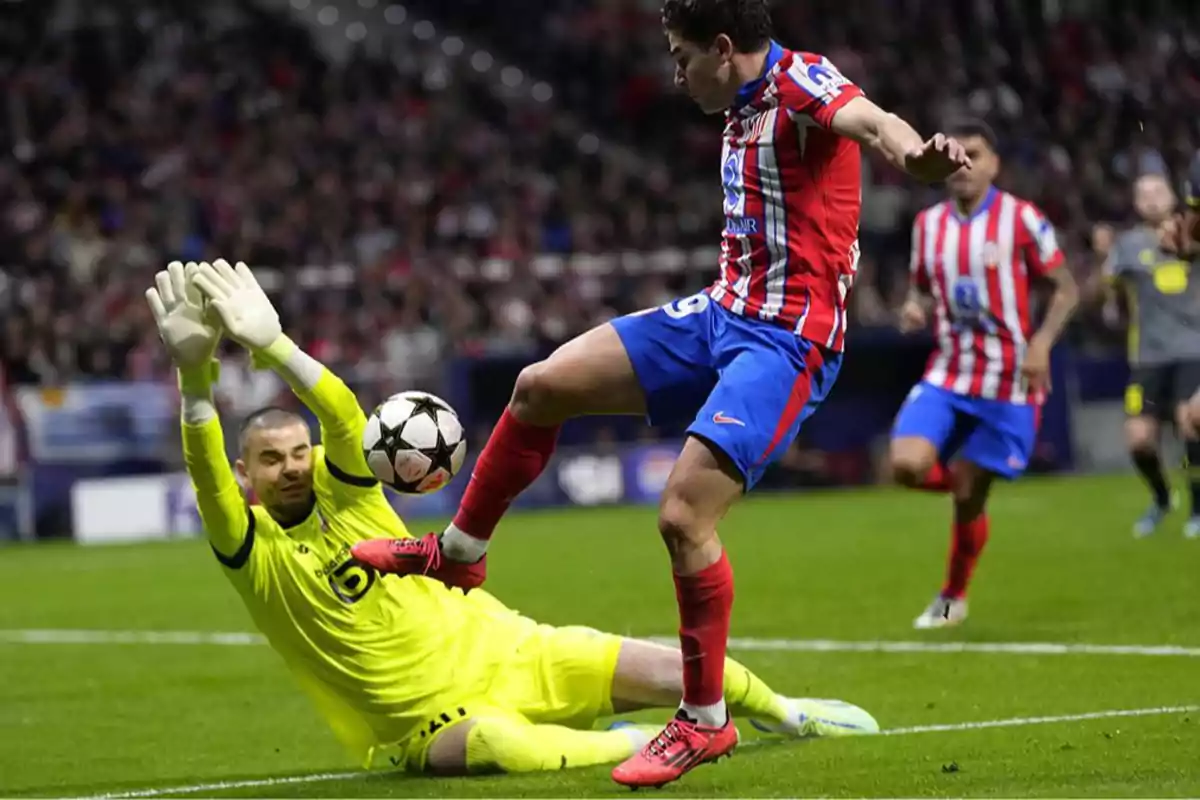 Goalkeeper in a yellow uniform tries to stop a shot from a forward in a red and blue uniform during a soccer match in a stadium full of spectators. Goalkeeper in a yellow uniform tries to stop a shot from a forward in a red and blue uniform during a soccer match in a stadium full of spectators.