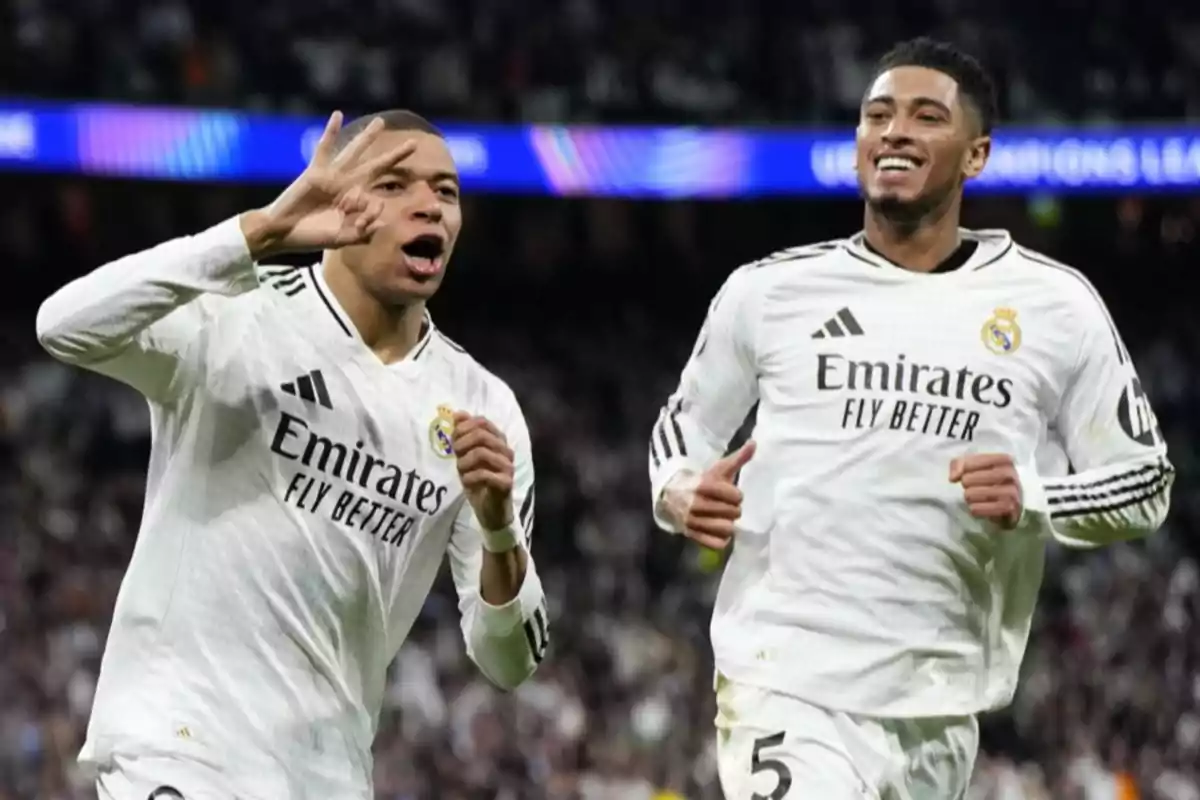 Two players in white uniforms celebrate on the field during a match.