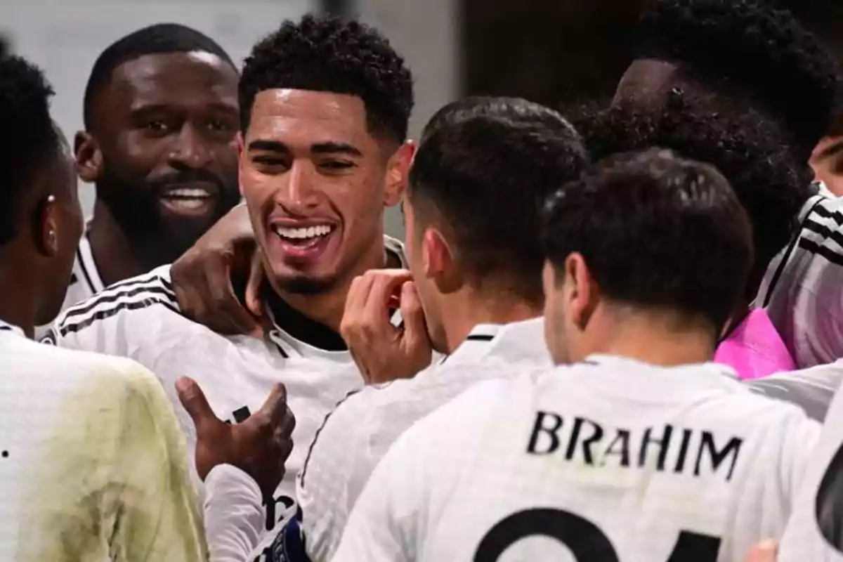 A group of soccer players celebrating together with smiles and hugs.