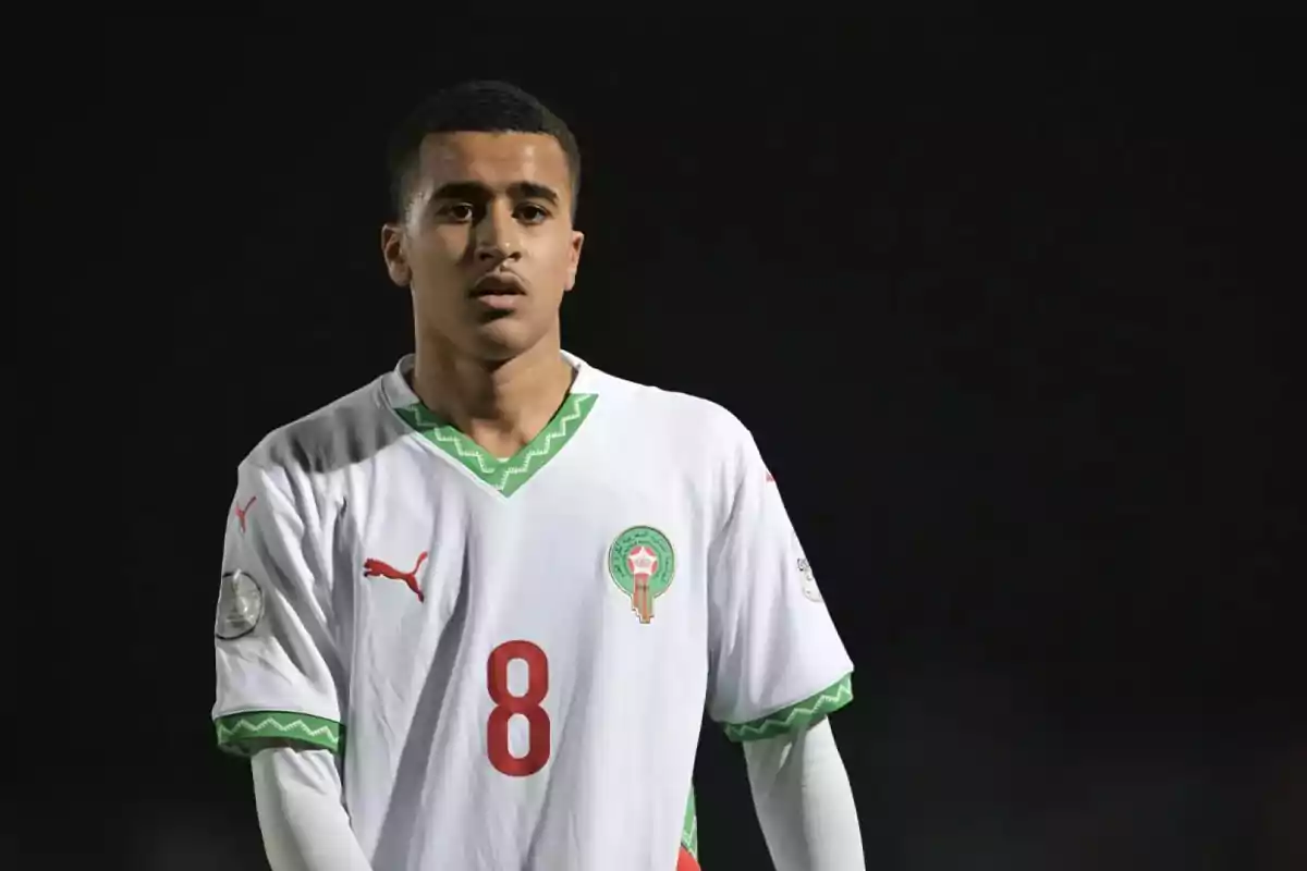 Soccer player wearing a white uniform with green and red details on a dark background Soccer player wearing a white uniform with green and red details on a dark background