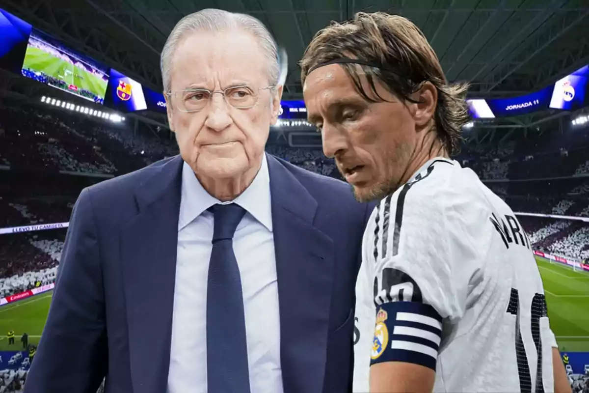 A man in a suit and a player in a white uniform in a stadium full of spectators.