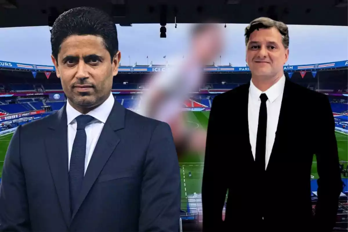 Two men in dark suits pose in front of a soccer stadium.