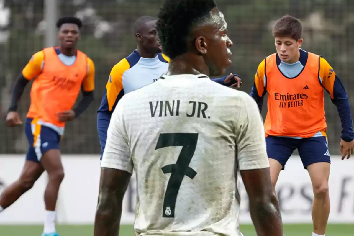 Jugadores de fútbol entrenando en el campo con camisetas de entrenamiento y un jugador destacado de espaldas con el número 7.