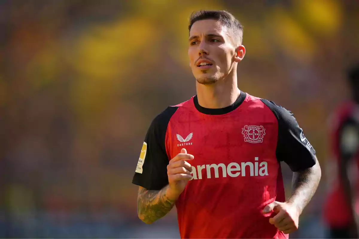 A player in a red and black Bayer Leverkusen uniform running on the field. A player in a red and black Bayer Leverkusen uniform running on the field.
