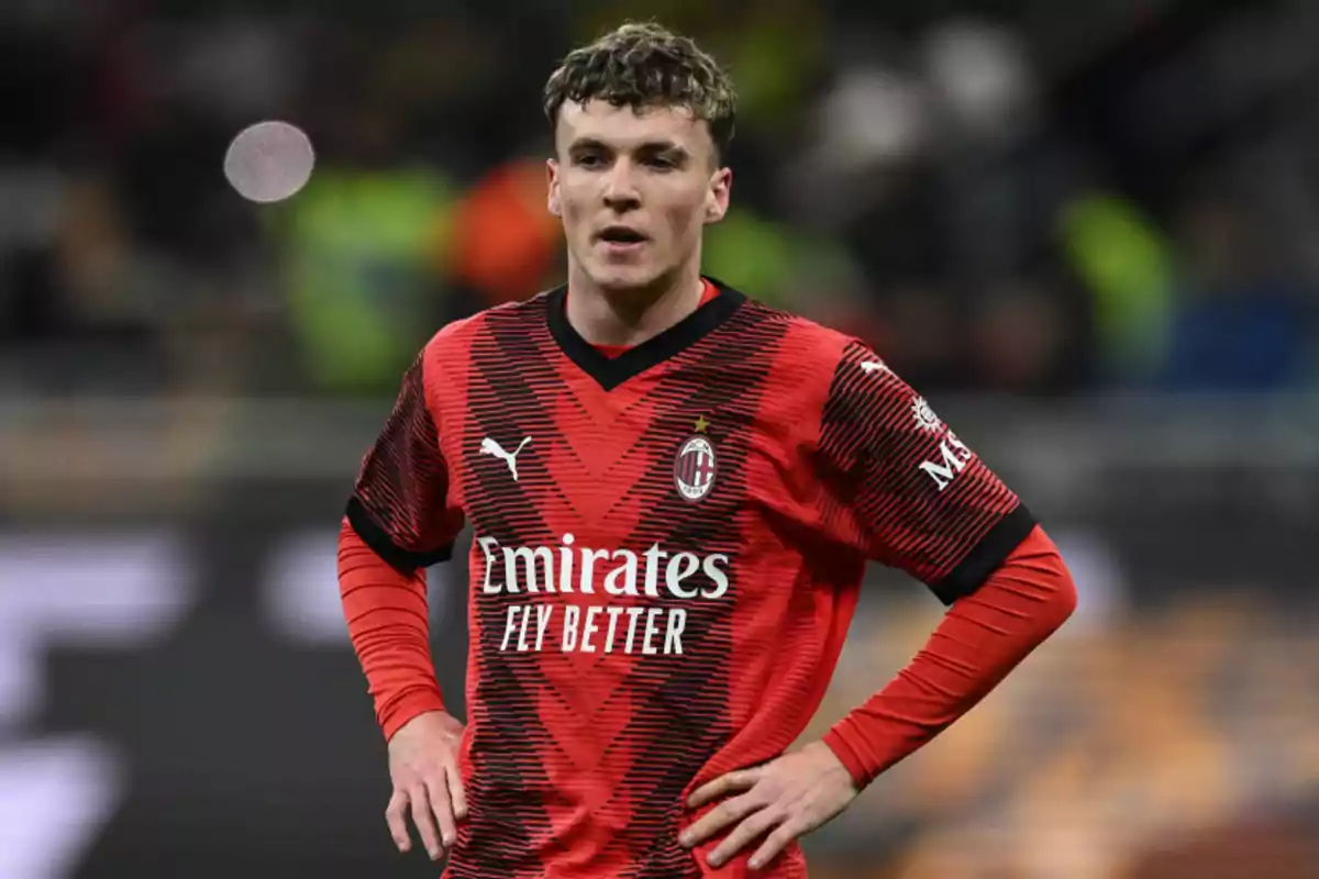 Jugador de fútbol con camiseta roja y negra del AC Milan en el campo.