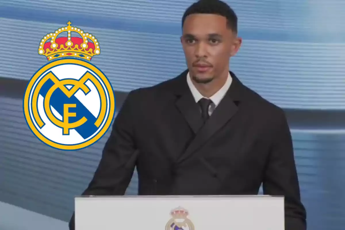 A man in a dark suit is standing in front of a podium with the Real Madrid crest, and the club’s logo appears prominently next to him.
