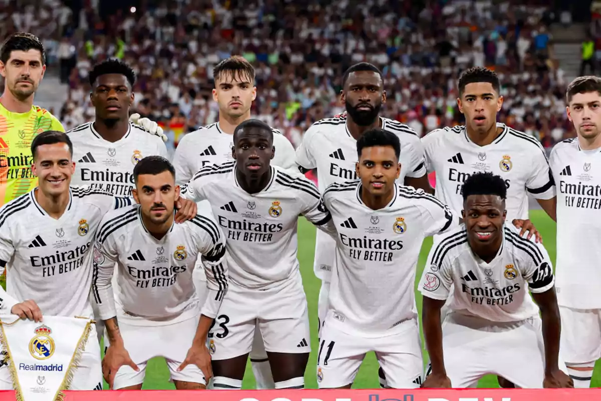 A group of Real Madrid players posing together on the field before a match, all wearing the team's white uniform with the sponsor's logo visible.
