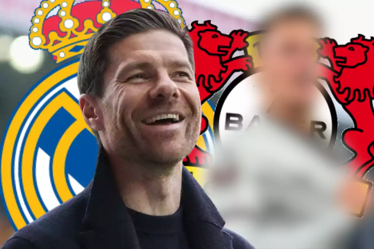 Un hombre sonriente con el logo del Real Madrid y el Bayer Leverkusen de fondo.
