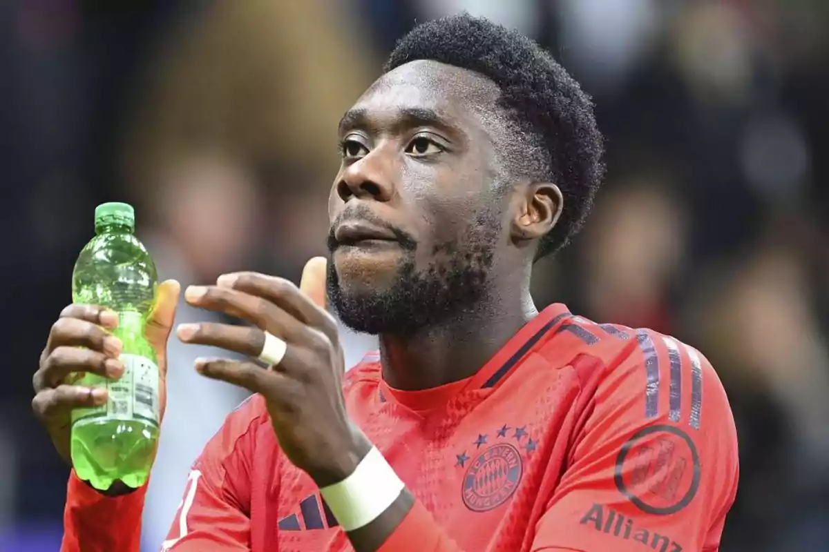 Football player in red uniform holding a green bottle. Football player in red uniform holding a green bottle.