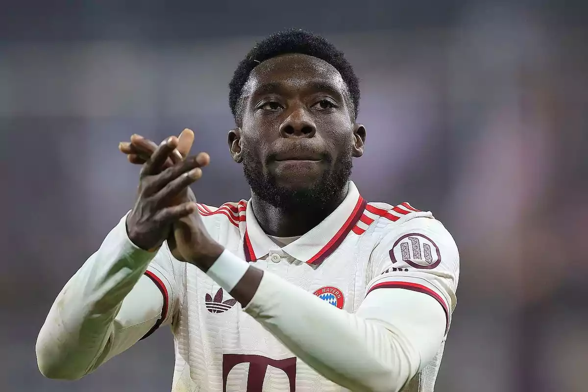 Un jugador de fútbol aplaudiendo en el campo con un uniforme blanco y rojo.