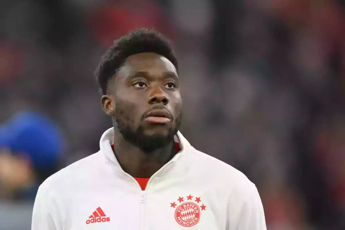 Football player in a white Bayern Munich jacket in a stadium.