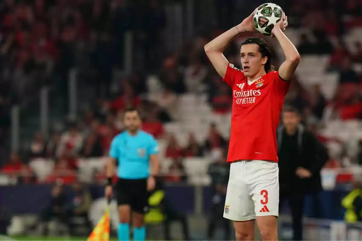 Benfica player in a red and white uniform prepares to take a throw-in during a match while a referee and the crowd can be seen in the background. Benfica player in a red and white uniform prepares to take a throw-in during a match while a referee and the crowd can be seen in the background.