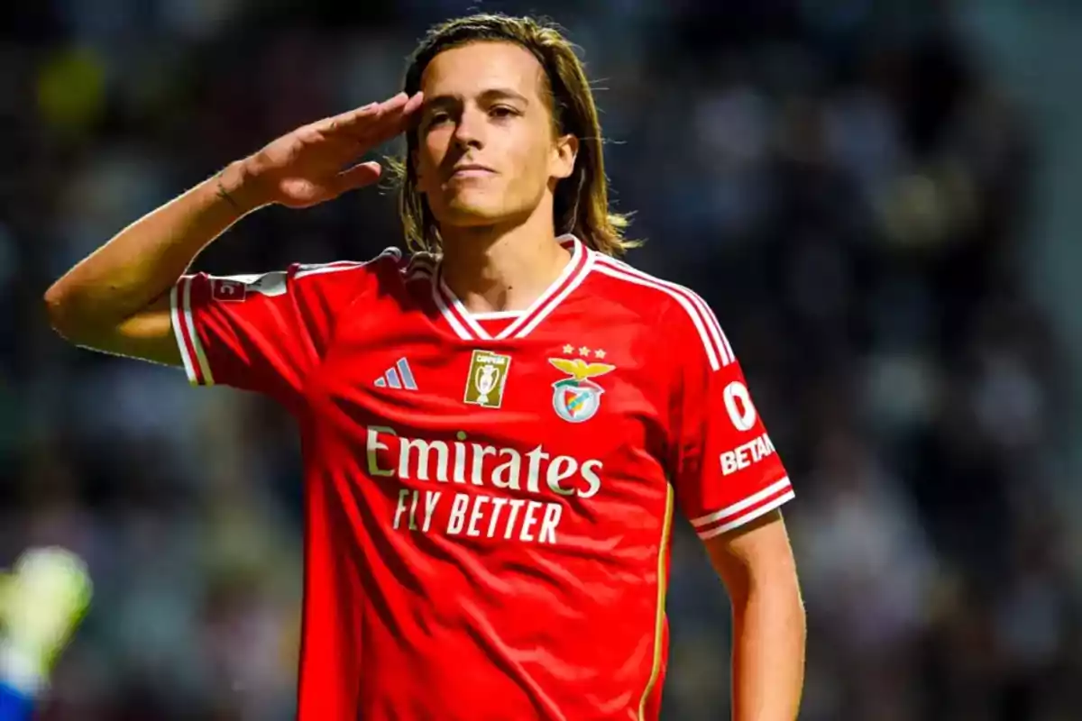 Soccer player in a red Benfica uniform giving a military salute on the field. Soccer player in a red Benfica uniform giving a military salute on the field.