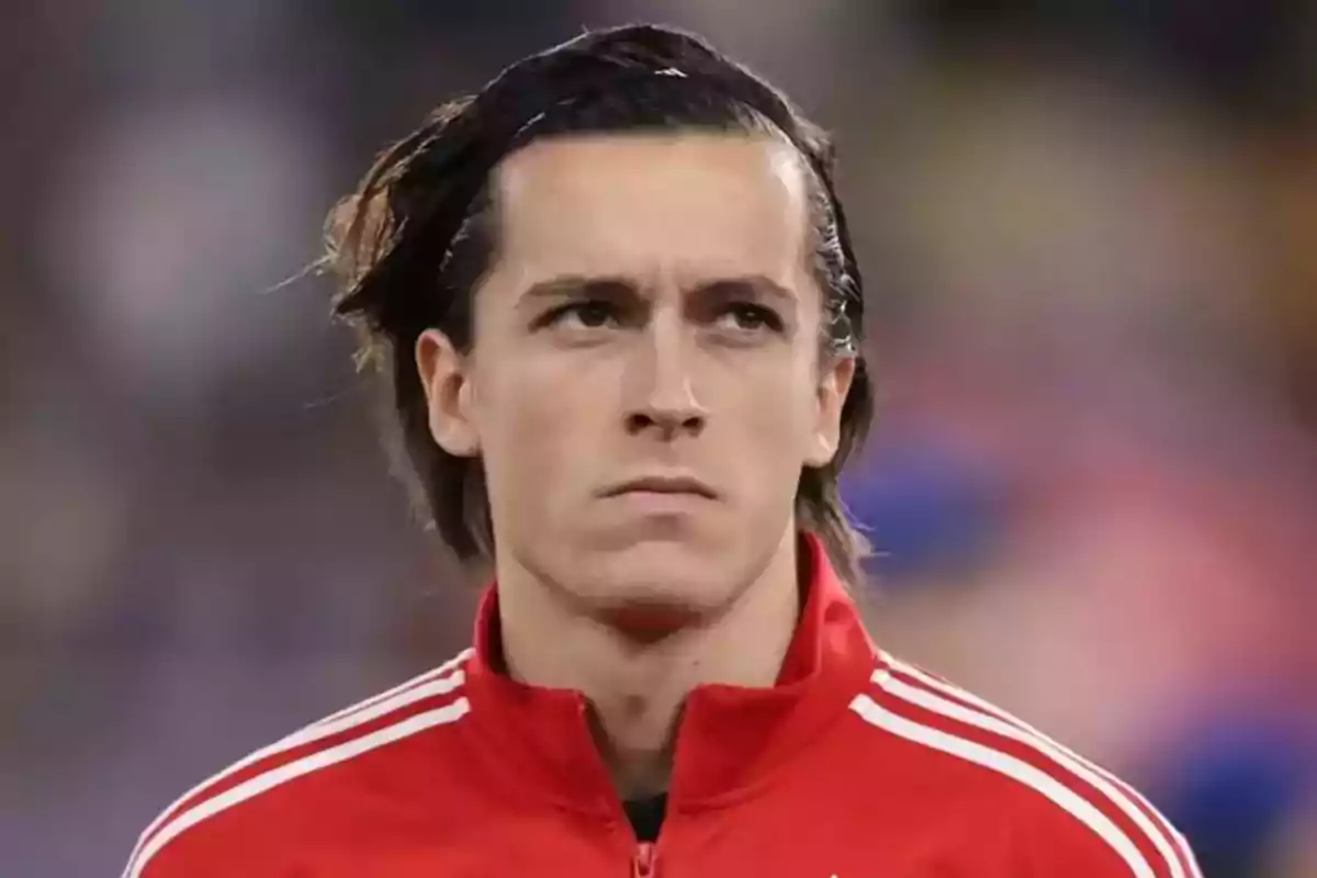 Joven con chaqueta deportiva roja mirando al frente con expresión seria Joven con chaqueta deportiva roja mirando al frente con expresión seria
