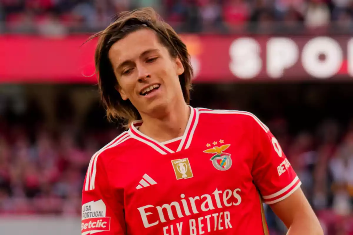 A football player wearing the red Benfica jersey on the field. A football player wearing the red Benfica jersey on the field.