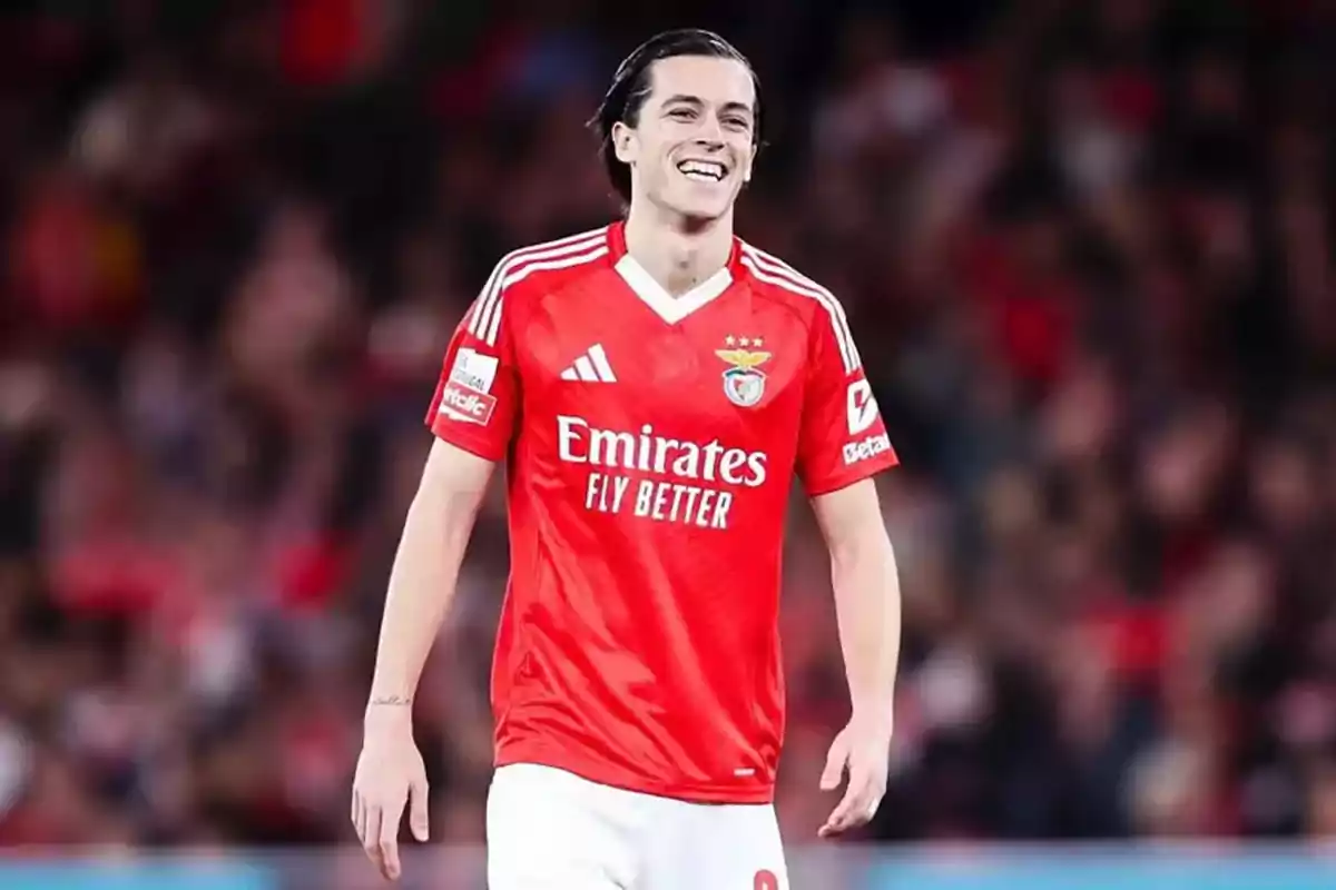 Soccer player in a red Benfica uniform smiling on the field