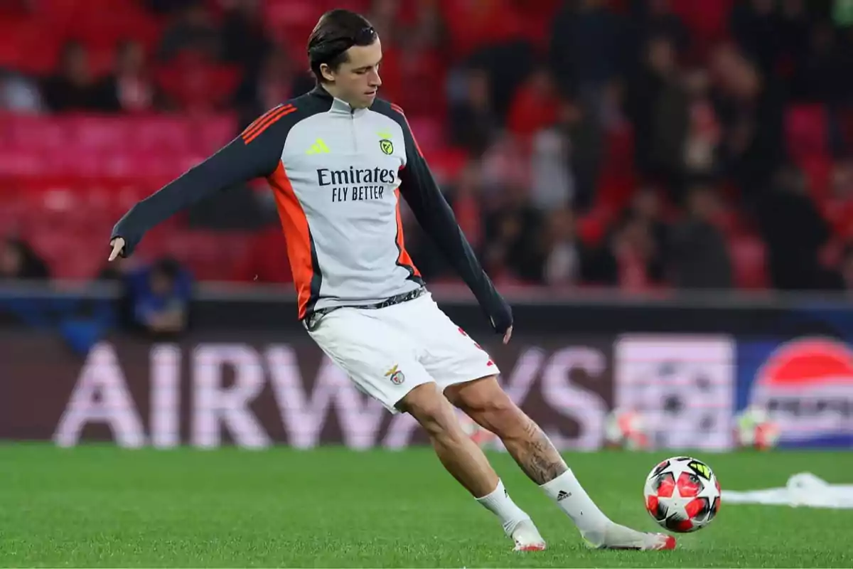 A player in a Benfica training uniform kicks a ball in a stadium. A player in a Benfica training uniform kicks a ball in a stadium.
