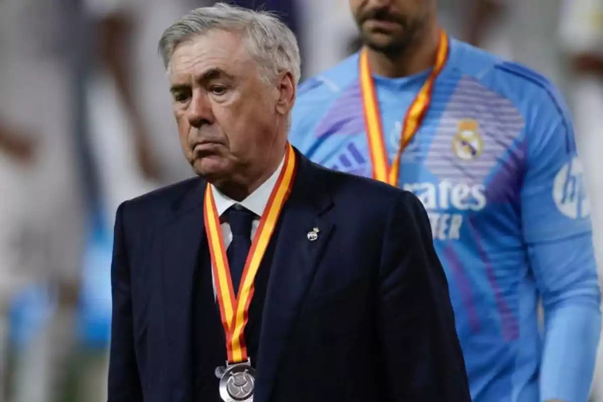 A man in a dark suit and a medal around his neck is standing in front of another person in a sports uniform. A man in a dark suit and a medal around his neck is standing in front of another person in a sports uniform.