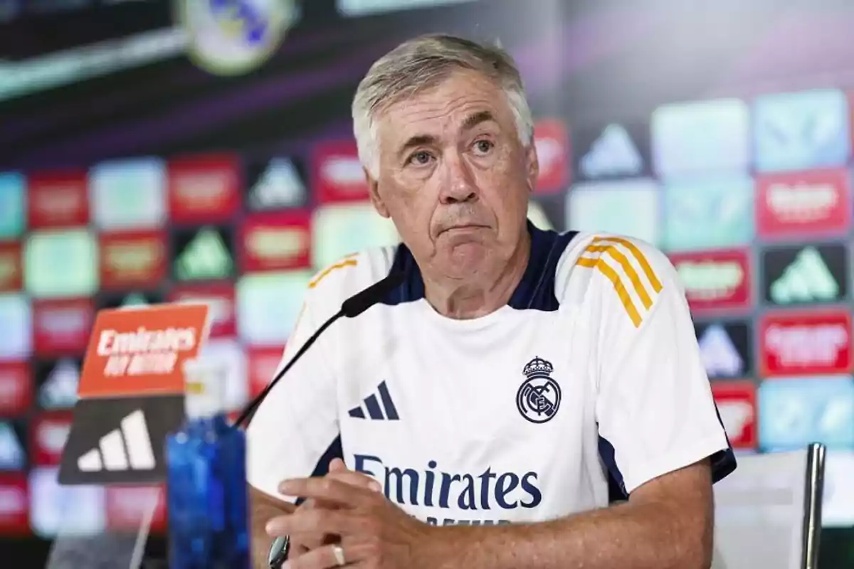 A man at a press conference wearing a soccer team jersey.