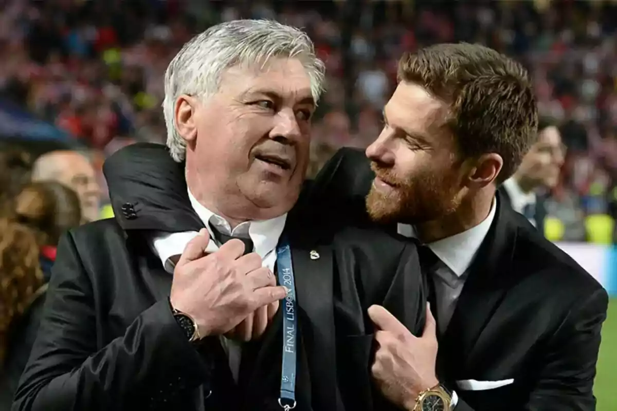 Two men in suits hug and smile in a crowded stadium. Two men in suits hug and smile in a crowded stadium.