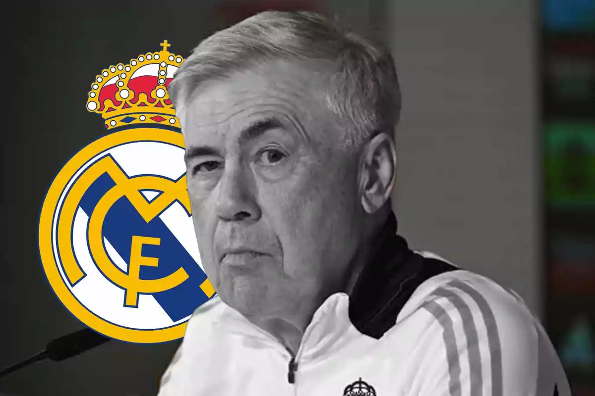 Un hombre con cabello canoso y expresión seria está frente a un micrófono con el escudo del Real Madrid en el fondo.