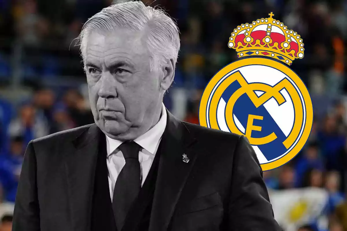 Un hombre de cabello canoso y expresión seria viste un traje oscuro, con el escudo del Real Madrid en el fondo.