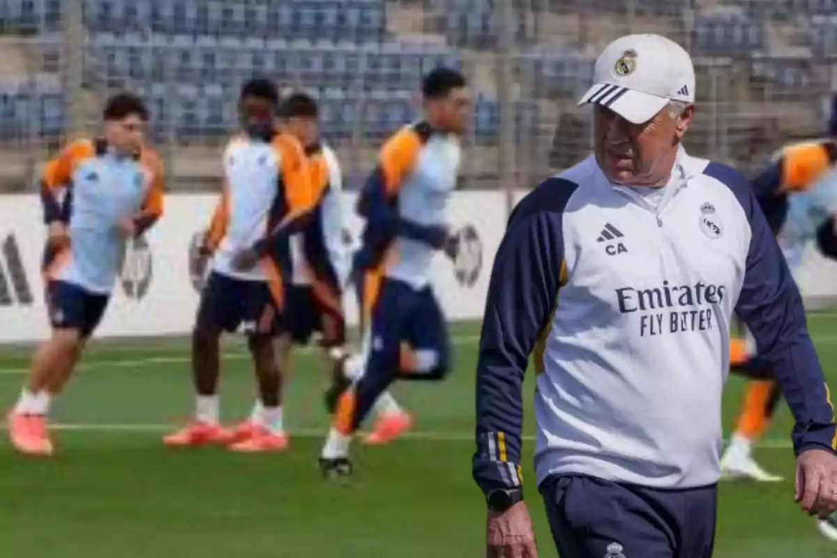 Un entrenador de fútbol observa a un grupo de jugadores entrenando en un campo.