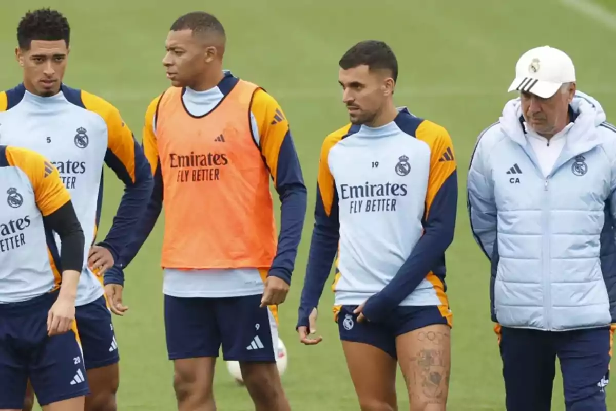 Un grupo de jugadores de fútbol y un entrenador en el campo de entrenamiento del Real Madrid.