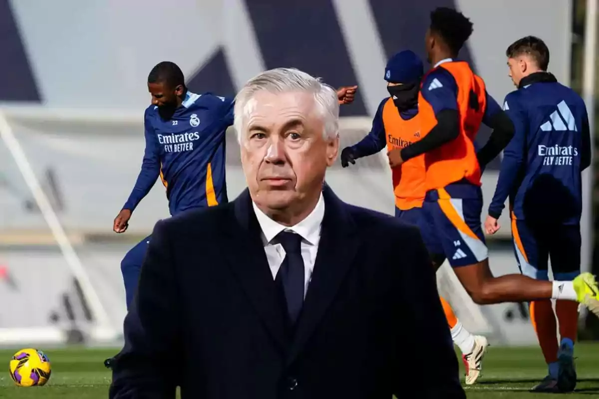 A soccer coach in the foreground with players training in the background.